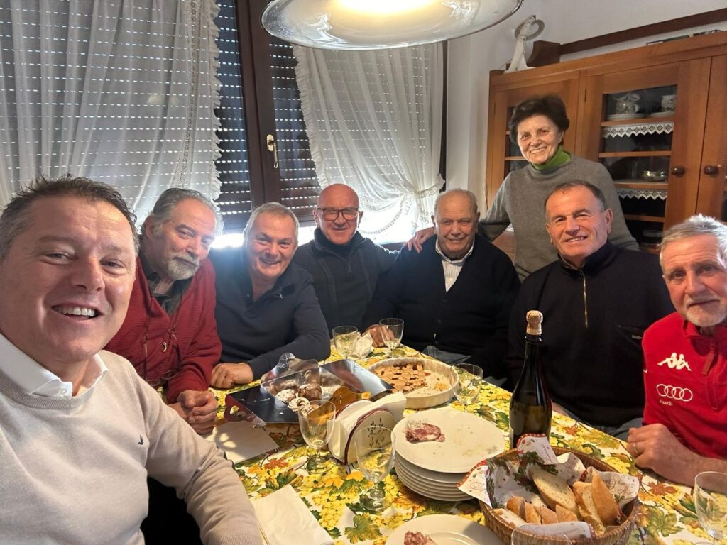 Un gruppo di amici attorno a una tavola apparecchiata in una cucina