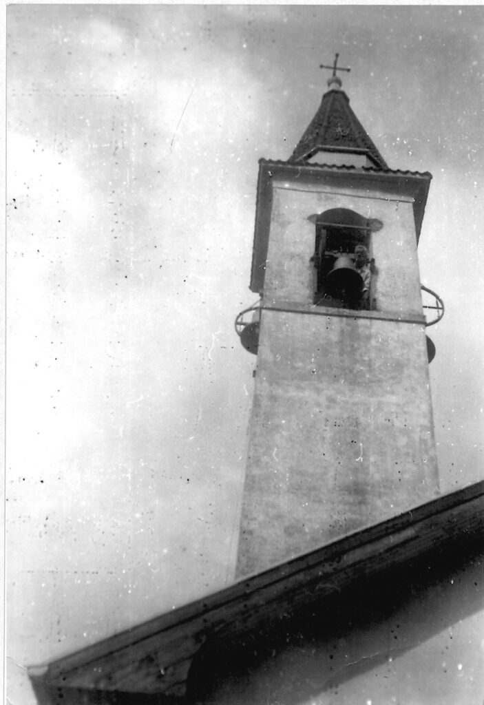 Il campanile visto dal basso, con un uomo affacciato alla cella campanaria