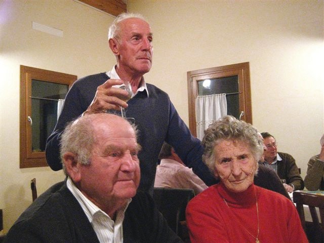 Mario De Luca, in piedi con un bicchiere in mano, accanto a Ernesto e Lidia Barattin seduti a tavola