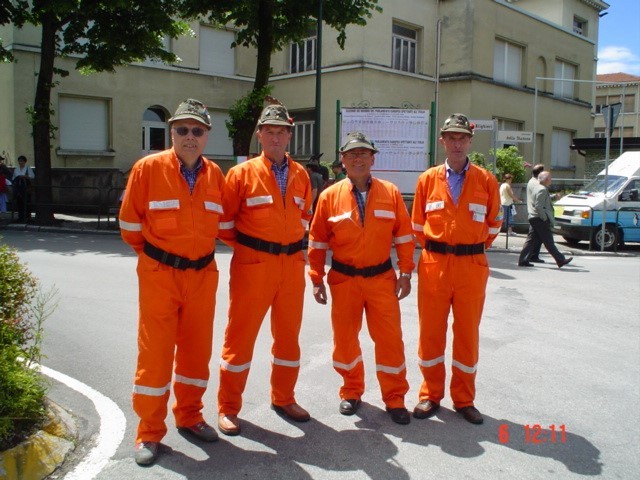 Quattro volontari della Protezione Civile del Gruppo Alpini di Salce in tuta arancione e cappello alpino: da sinistra Elio Marchetti, Bruno Boito, Toni Fratta e Attilio Boito
